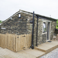 Outside with decked patio area, lawn, picnic table and seating